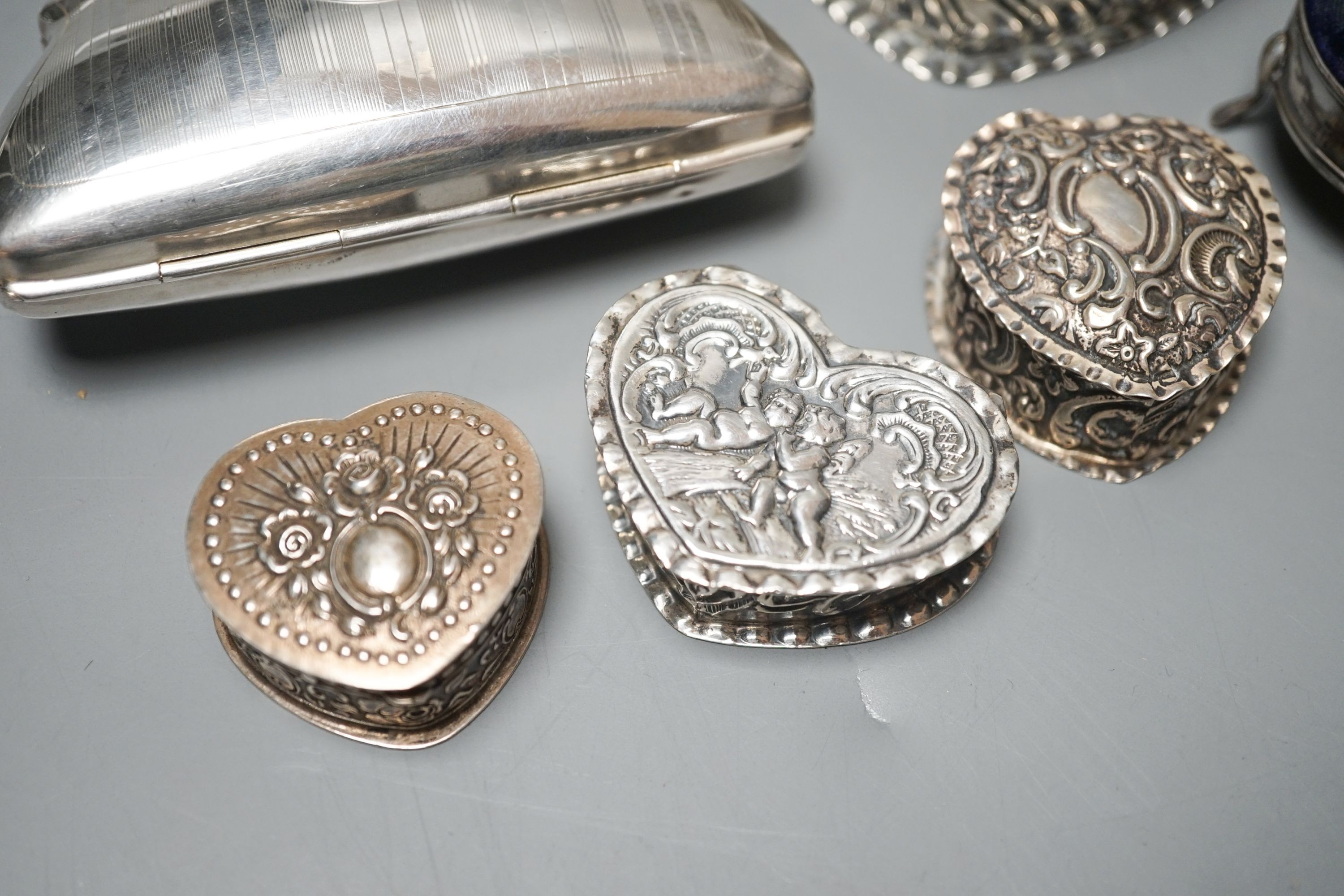 Four assorted silver or white metal heart shaped trinket boxes, largest 85mm a silver pin cushion and a silver purse.